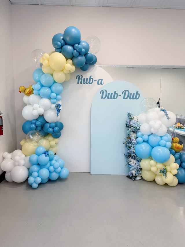 Layered white and blue arched backdrops with an organic blue, white, and cream balloon garland