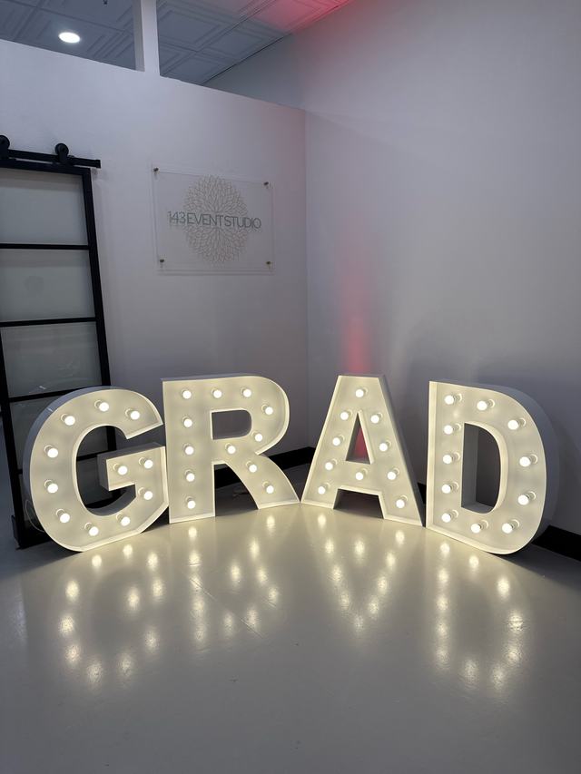 Light-up marquee letters spelling GRAD