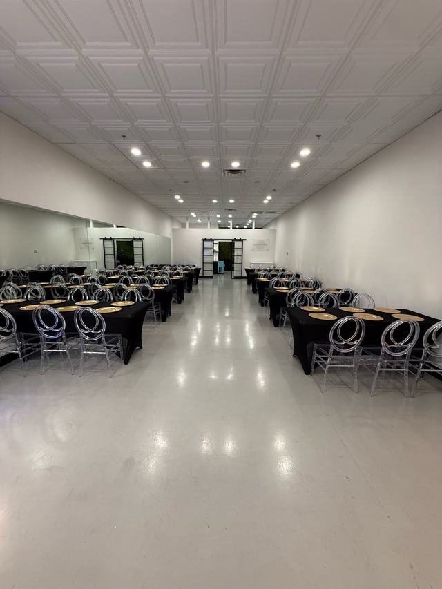 Black-and-gold table setup with ghost chairs down the length of the room
