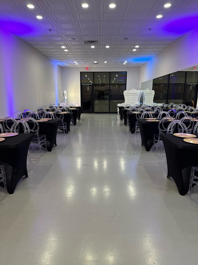 The studio with purple uplighting and black-linen tables lining both walls